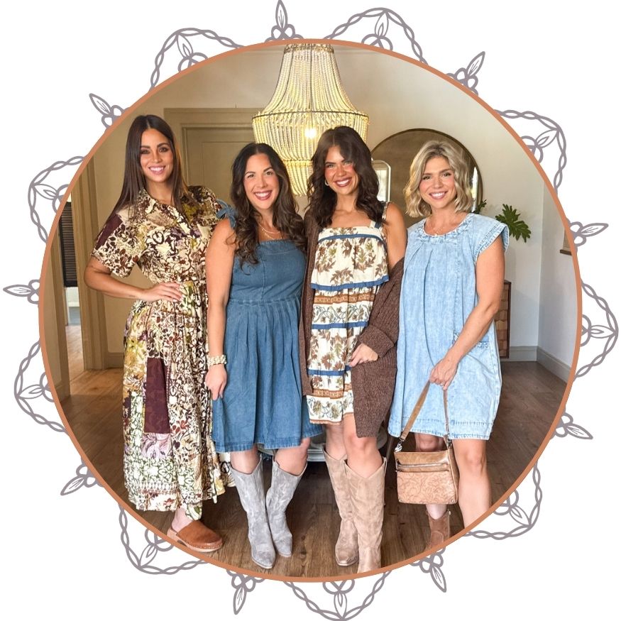 Four women posing together in a room with a chandelier.