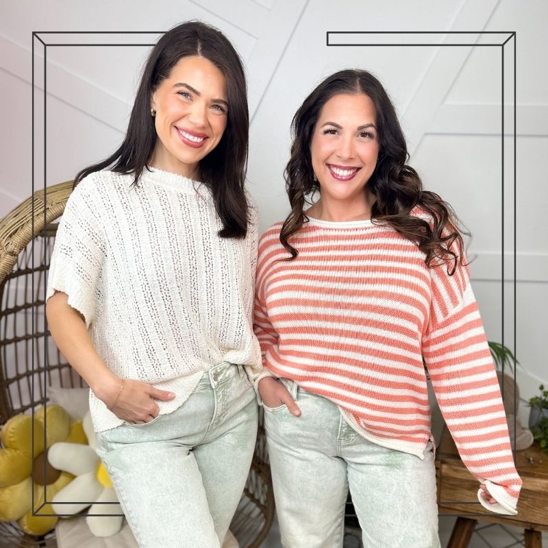 Two women posing together in a casual setting with a white wall and decorative elements.