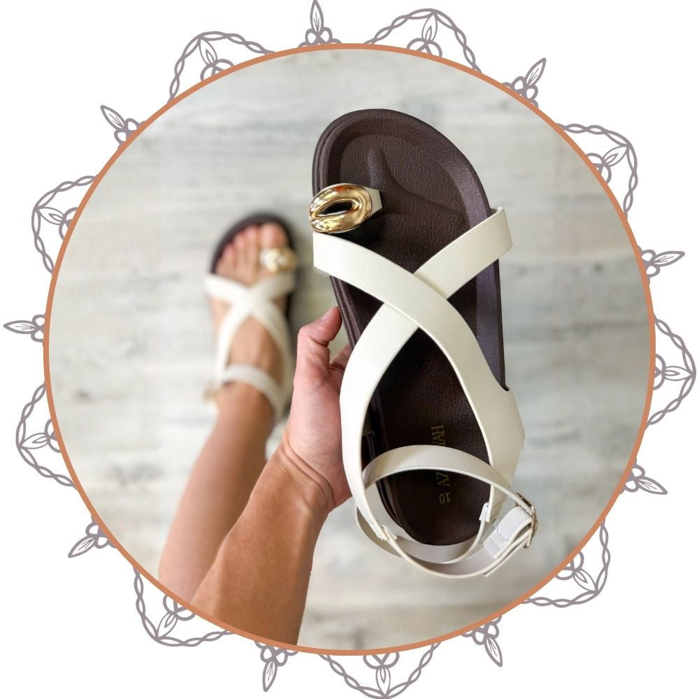 White sandal with gold buckle being worn on a marble surface | Heathered Boho Boutique | Palmetto, FL